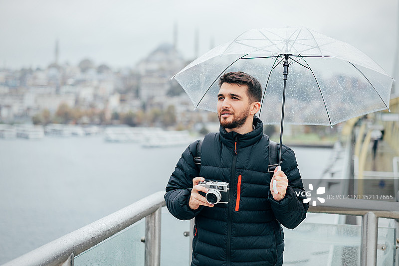 在雨天用相机拍照的男游客图片素材