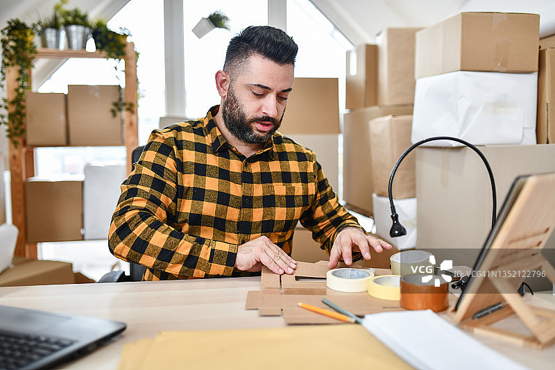 在配送中心折叠箱子的英俊男工人图片素材