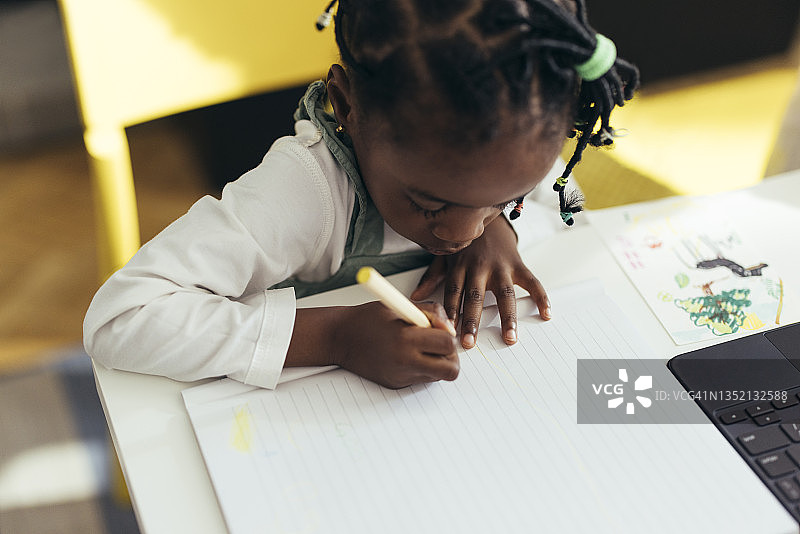 在客厅用彩色铅笔画画的可爱小女孩图片素材