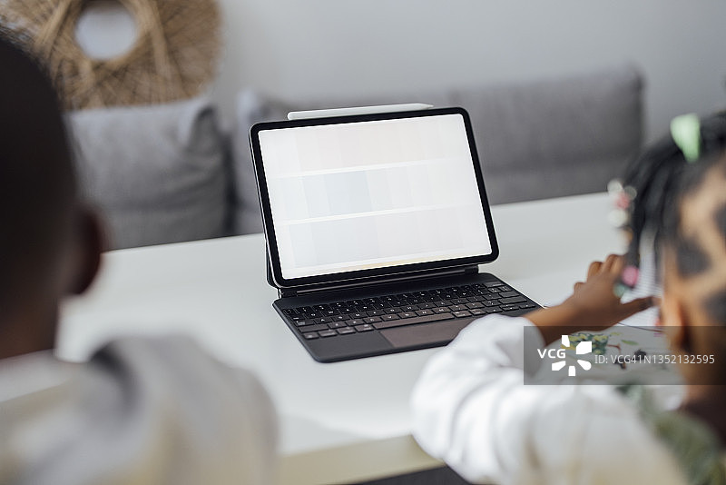 无法辨认的兄弟姐妹在客厅里一起做作业图片素材