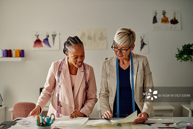 年长的和年轻的成人时装设计师在看草图图片素材