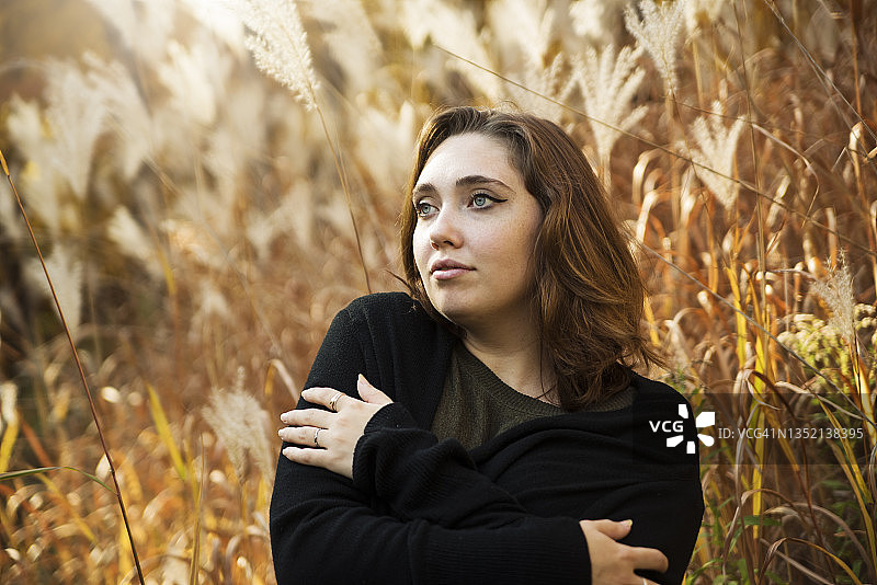 秋日自然中拥抱自己的年轻女子肖像图片素材