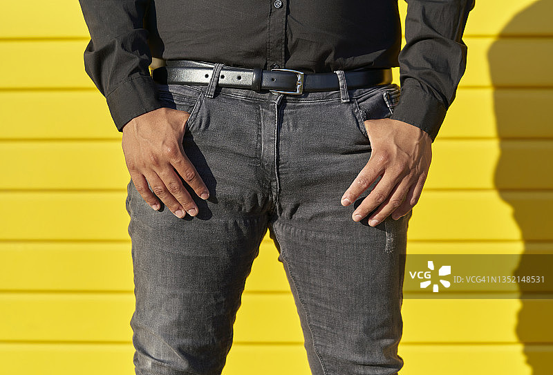 黄色背景中双手插在口袋里的黑衣男人半身像特写图片素材