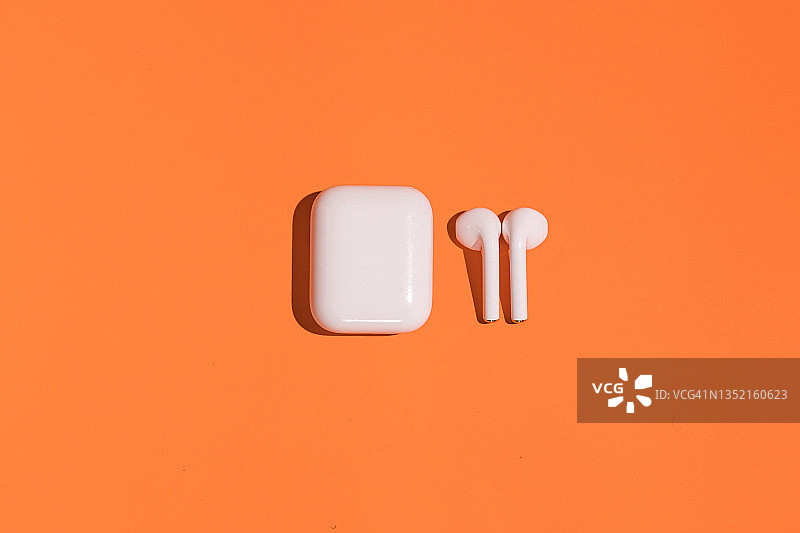 橙色背景上的无线白色耳机图片素材