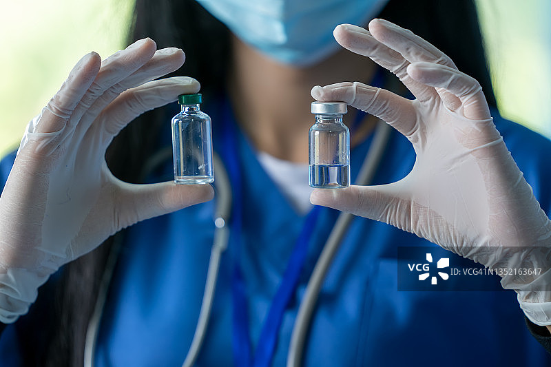 医生或科学家在实验室里拿着装有新冠疫苗的小瓶，准备进行流感疫苗注射。图片素材