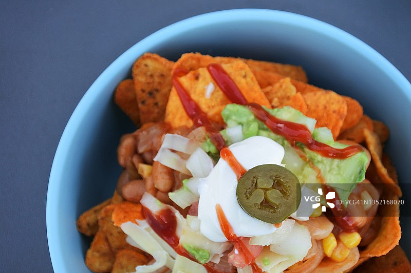 碗中盛放着豆子、牛油果、萨尔萨酱和墨西哥辣椒的玉米片图片素材