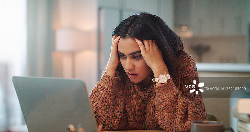 年轻女人在家用笔记本电脑学习，看起来压力很大的照片图片素材