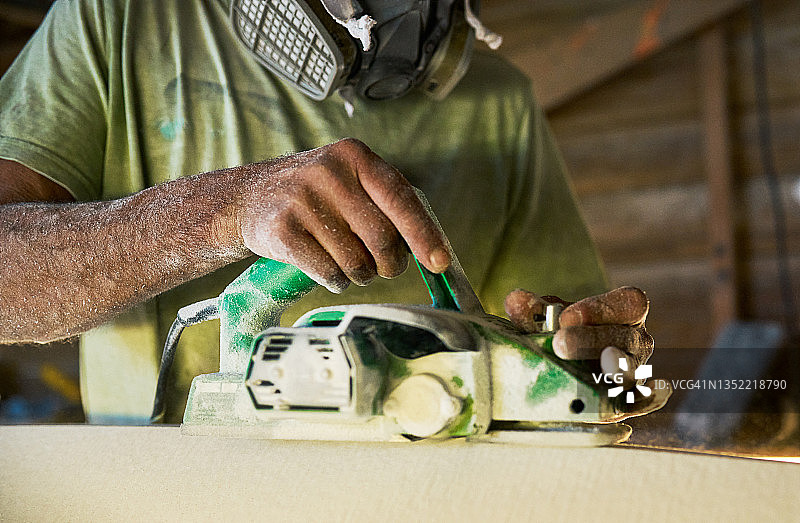 一位木匠在棚屋里独自制作冲浪板的局部照片图片素材