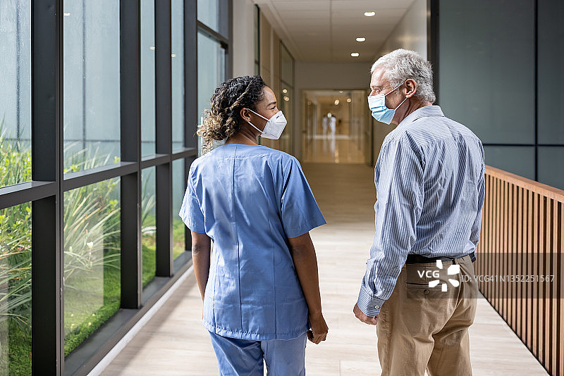 医生在医院走廊戴口罩与病人交谈图片素材