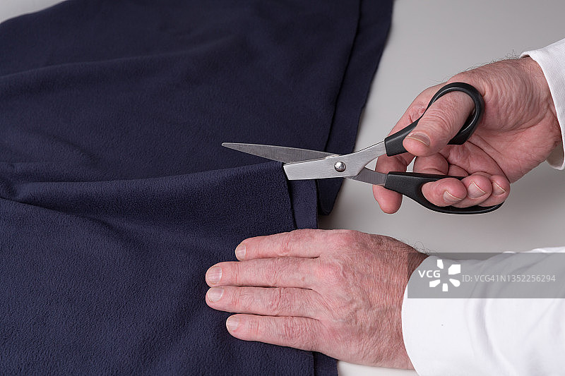 裁缝裁剪布料的特写。服装商在工作中裁剪布料。图片素材