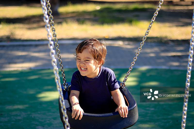 在公园荡秋千的快乐小男孩图片素材