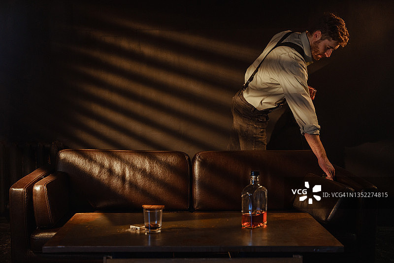 孤独的胡须男人在房间里手持威士忌酒杯的氛围照片图片素材