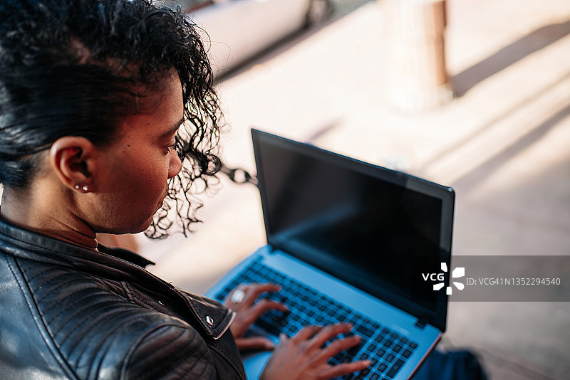 在街上使用笔记本电脑的西班牙裔女性图片素材