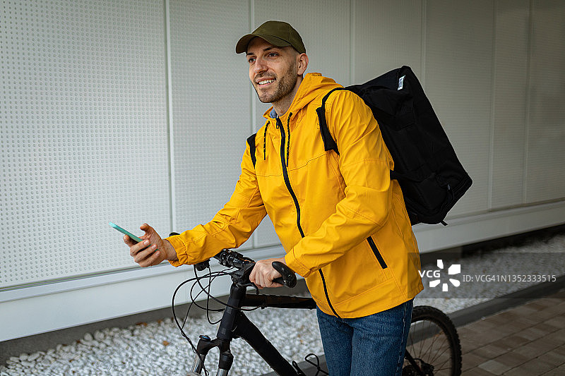 食品配送员试图在手机上找到正确的地址图片素材