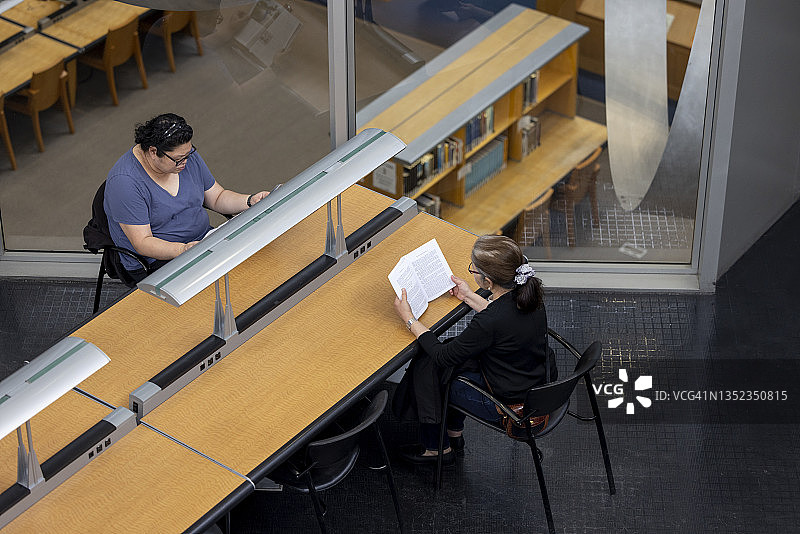两位女人在公共图书馆阅读图片素材
