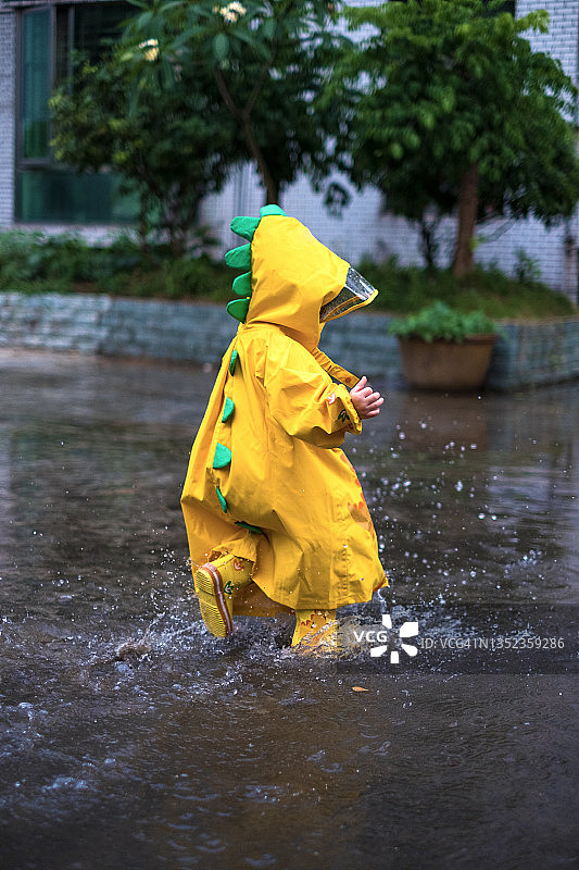 穿着黄色雨衣享受雨天的小女孩图片素材