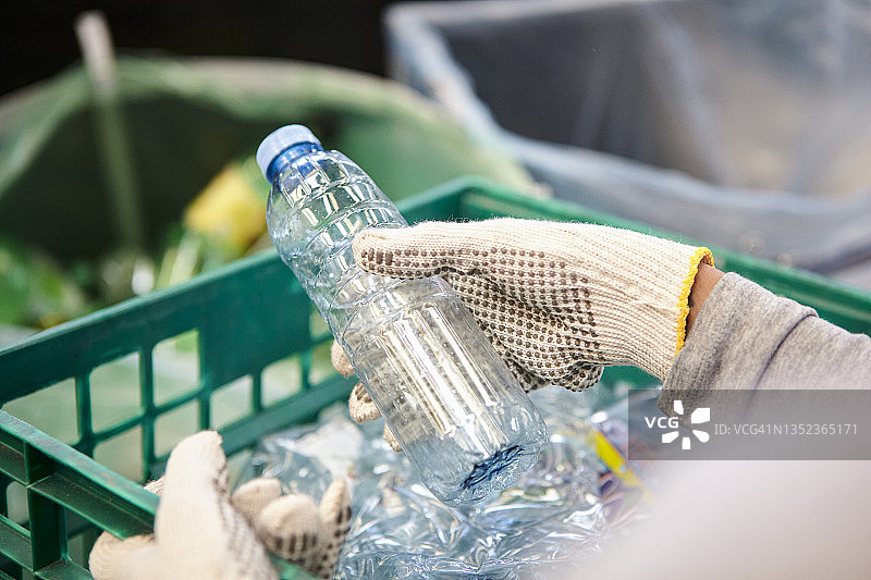 戴着工作手套拿着塑料瓶的垃圾管理工人图片素材