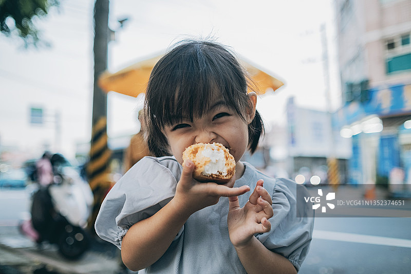 小女孩高兴地吃奶油泡芙图片素材