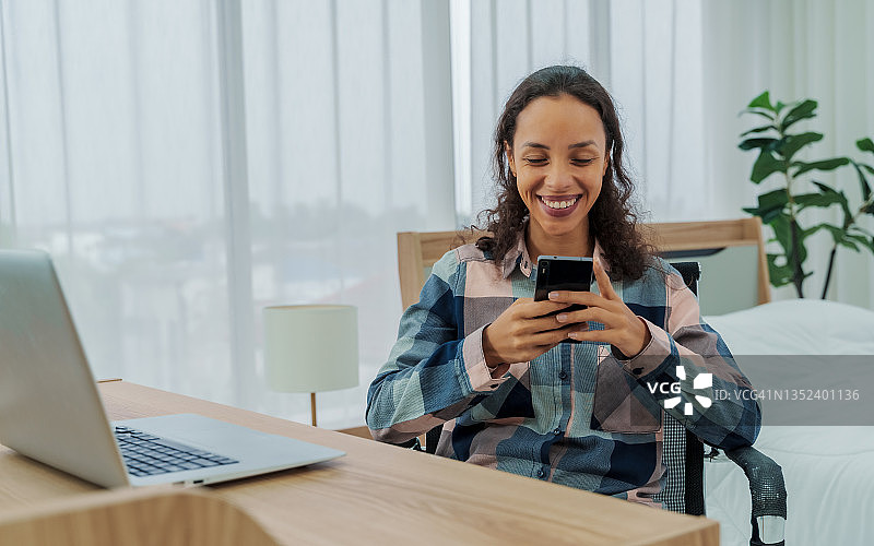 在办公桌前用智能手机发短信的迷人女性图片素材