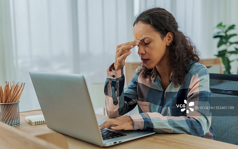 在家工作后感到眼睛疲劳的疲惫女士，头痛、视觉疲劳和眼睛疲劳概念图片素材