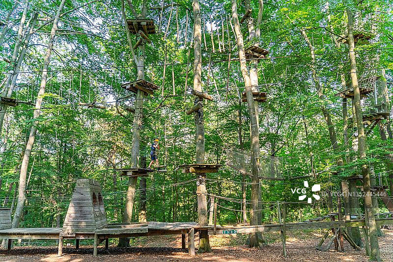 男孩在波茨坦探险公园的攀爬森林和高空绳索课程中攀爬图片素材