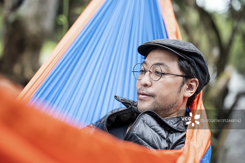 在吊床上露营小憩的日本男人：户外活动，自然与露营爱好者图片素材