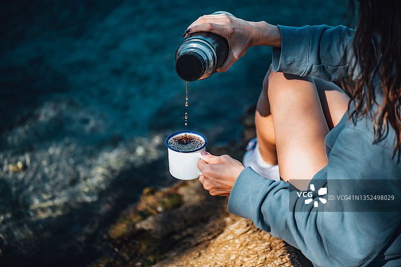 在海滩上用保温杯喝咖啡的女人图片素材