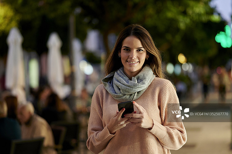 黄昏时在街上使用智能手机的女人图片素材
