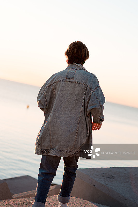男孩奔向大海，日出时的模特，生活方式，男孩从背后看图片素材