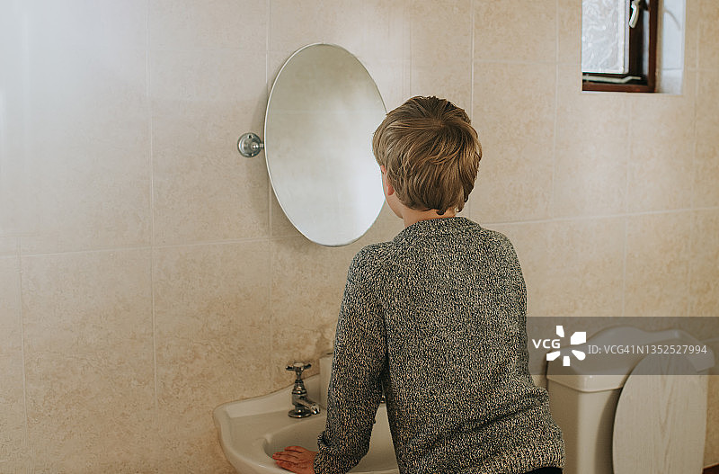 小男孩照着浴室镜子图片素材