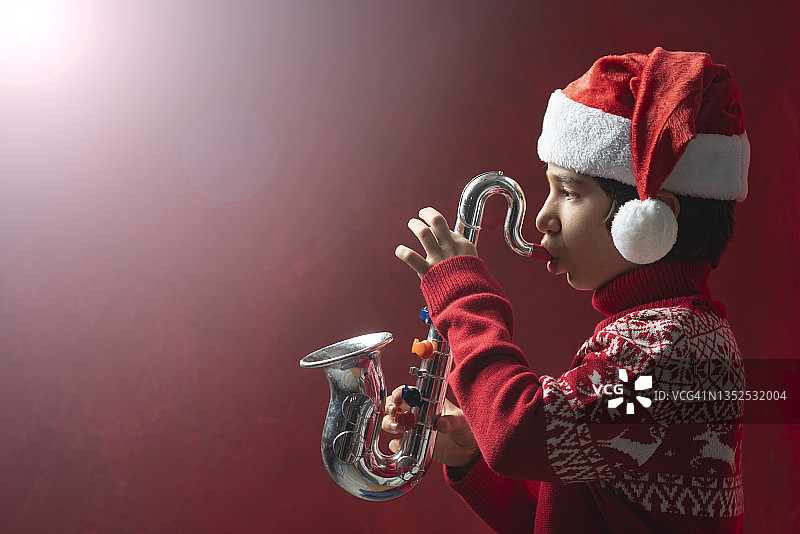 戴着圣诞帽吹萨克斯的男孩图片素材