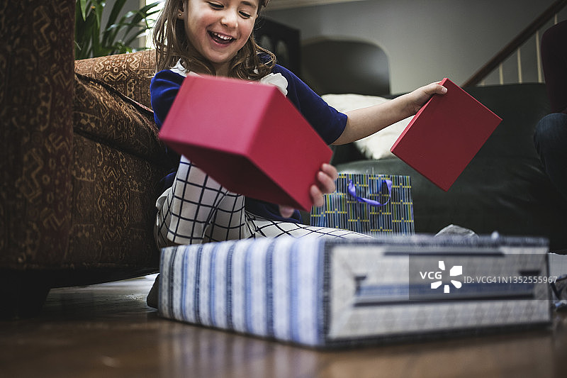女孩在客厅里打开光明节礼物图片素材