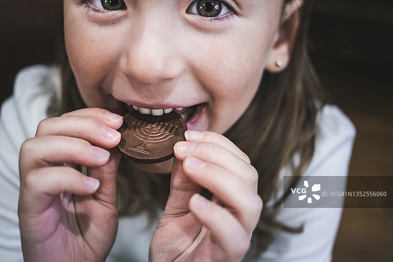 小女孩吃巧克力币特写图片素材