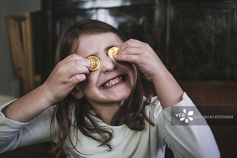 女孩用巧克力遮住眼睛，做着滑稽的表情图片素材