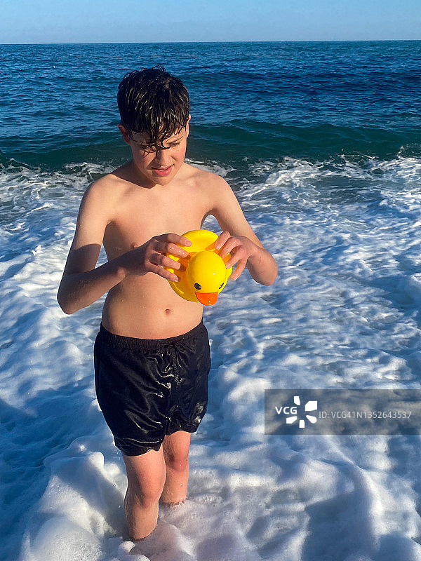 在海中挤压橡皮鸭的青少年图片素材