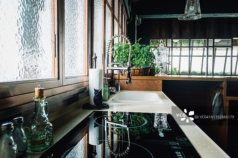 现代开放式厨房的温馨内饰，配有厨房用品和烹饪用具，阳光透过窗户照射进来图片素材