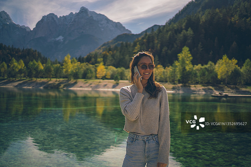 年轻女人在秋季高山湖泊附近放松图片素材