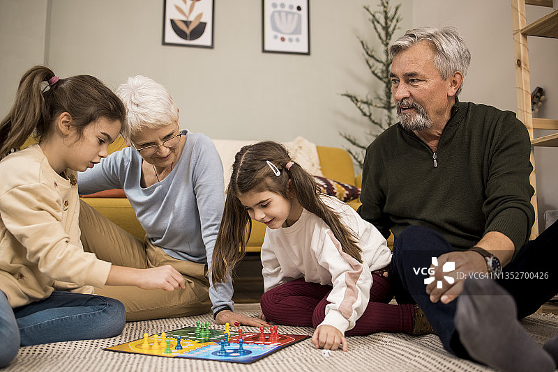 两个可爱的女孩在爷爷奶奶家玩棋盘游戏图片素材