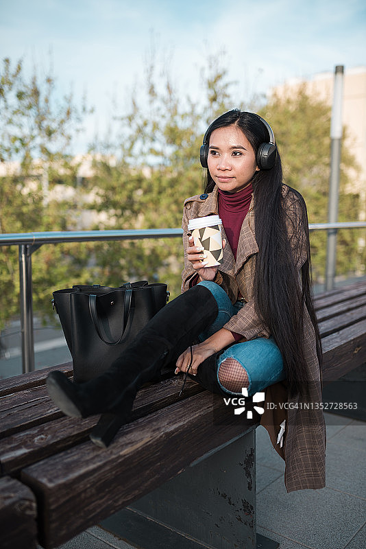 亚洲女人在长椅上听音乐图片素材