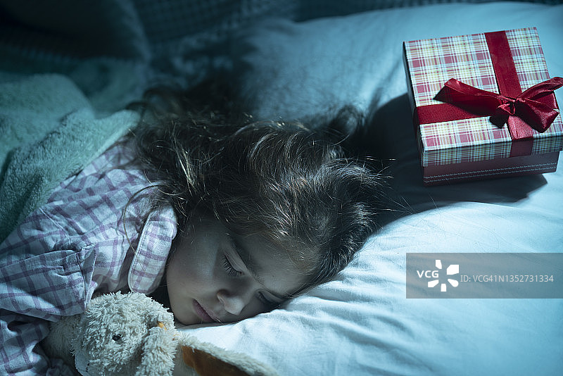 枕头上放着圣诞礼物的熟睡小女孩照片图片素材