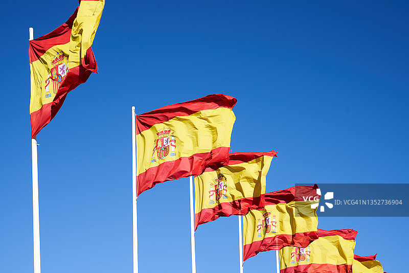 许多西班牙国旗在蓝天下迎风飘扬图片素材