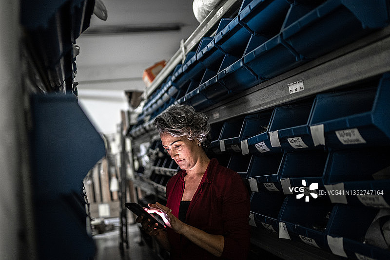 在储藏室里使用手机的中年妇女图片素材