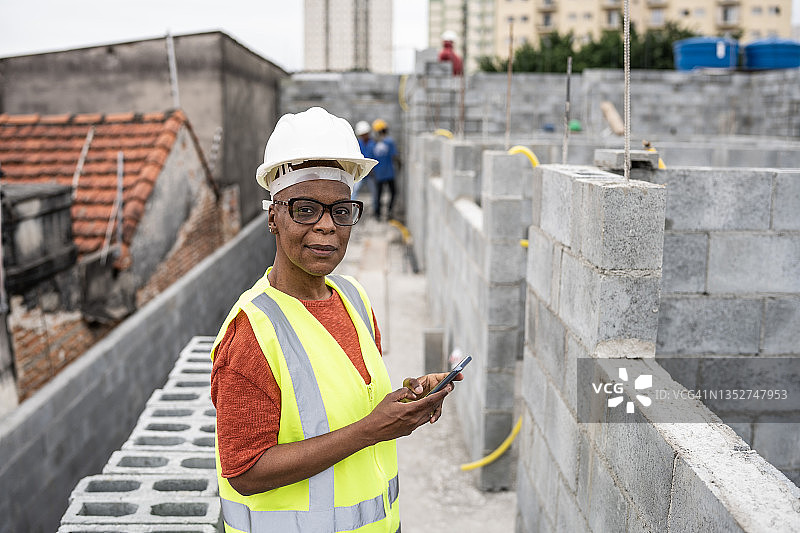 在建筑工地使用智能手机的中年女工程师肖像图片素材