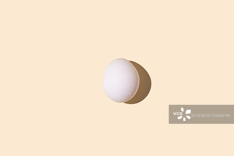 柔和黄背景上带硬阴影的白色鸡蛋图片素材