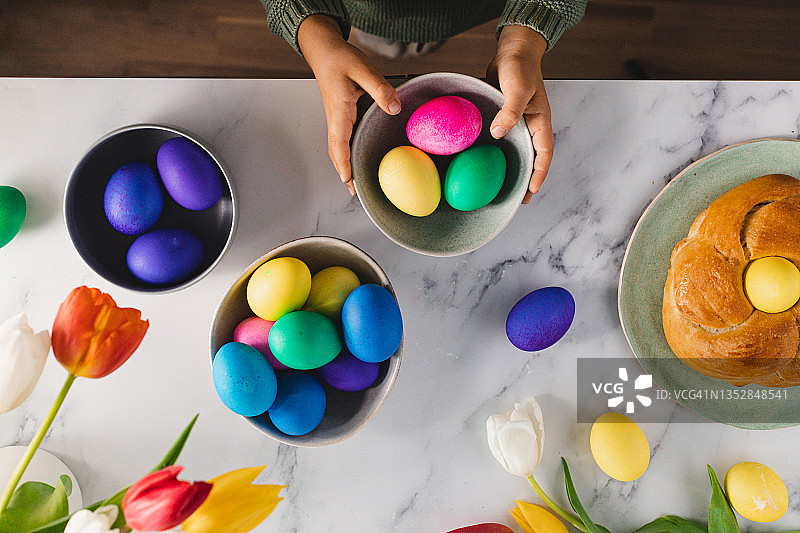 在云石桌旁拿着彩色复活节彩蛋的小男孩图片素材