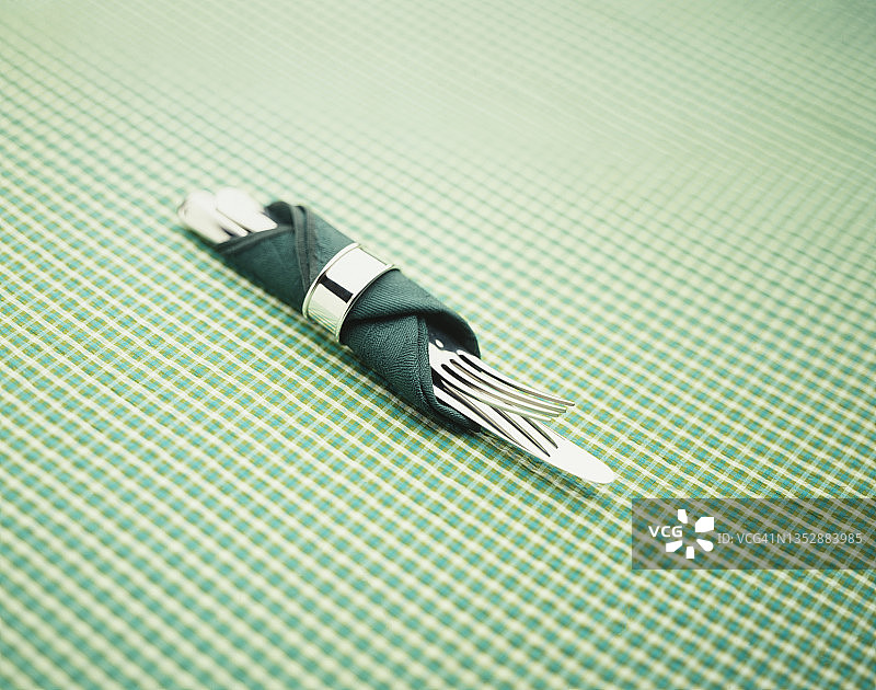 绿色餐巾包裹的刀叉与餐巾环图片素材