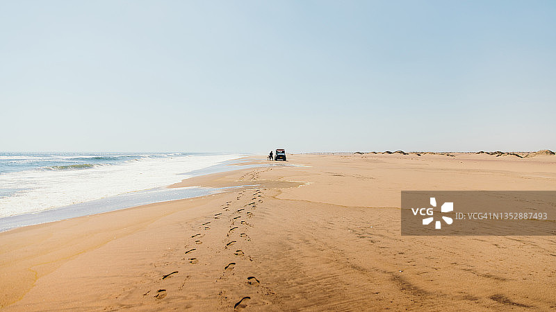男人在纳米布沙漠的荒野沙滩上靠近4X4汽车图片素材