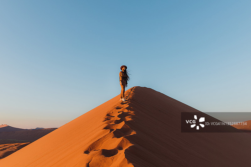 女游客在纳米布沙漠的沙丘上欣赏日出美景图片素材
