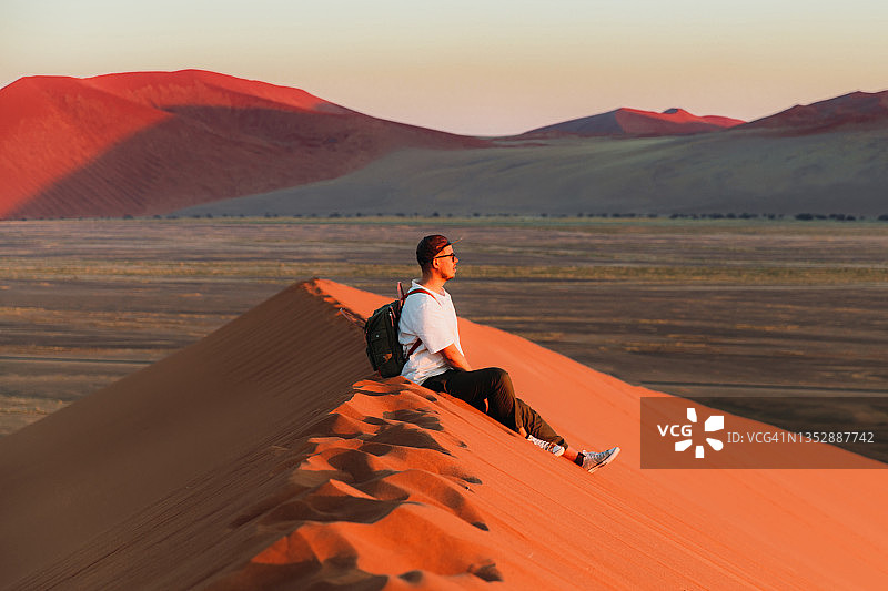 旅行者沉思纳米布沙漠沙丘上的壮丽日出图片素材
