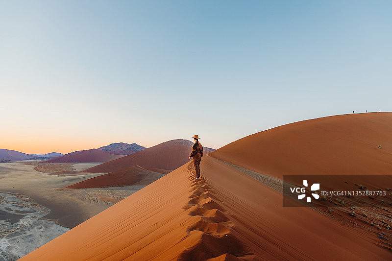 女游客在纳米布沙漠的沙丘上欣赏日出美景图片素材